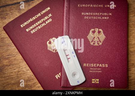 Augsbourg, Bavière, Allemagne - 1er août 2024 : test COVID-19 positif aux côtés de deux passeports. Image symbolique annulation des vacances d'été prévues en raison d'une maladie à coronavirus en été. PHOTOMONTAGE *** positionneur Ein COVID-19 test neben zwei Reisepässen. Symbolbild Absage des geplanten Sommerurlaub aufgrund einer Coronavirus Erkrankung im Sommer. FOTOMONTAGE Banque D'Images