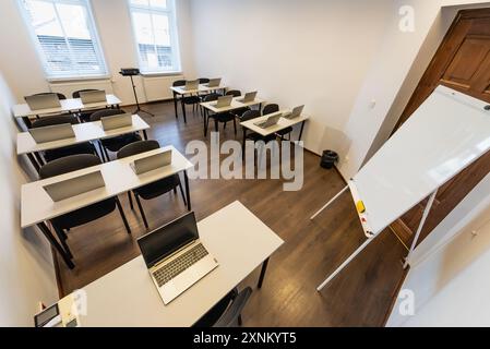 Intérieur d'une salle de classe moderne avec bureaux, chaises et ordinateurs portables. Salle de conférence vide avec ordinateur portable sur table dans le bureau. Office Business. Salle de conférence Banque D'Images