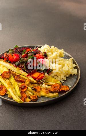 Dégustez un copieux petit déjeuner ou un déjeuner avec millet, courgettes cuites au four et carottes, accompagnés d'une salade fraîche de légumes et d'herbes de saison, pour un déliciou Banque D'Images