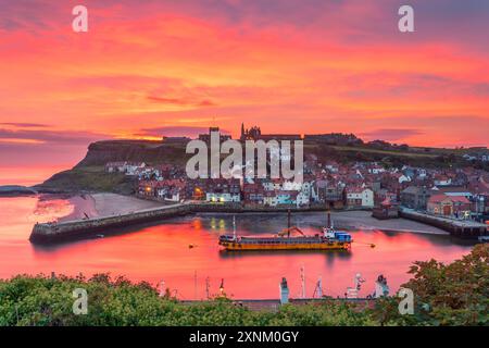 Un navire de dragage dans le port alors que le soleil se lève sur Whitby et la rivière Eske, côte du Yorkshire du Nord, Angleterre Banque D'Images