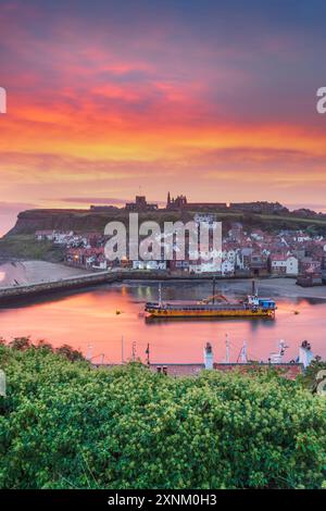 Un navire de dragage dans le port alors que le soleil se lève sur Whitby et la rivière Eske, côte du Yorkshire du Nord, Angleterre Banque D'Images