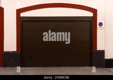 Porte de garage brune fermée avec garniture rouge et pas de panneau de stationnement Banque D'Images