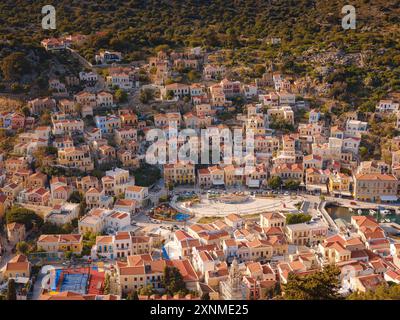 Île de Symi, Grèce - 20 avril 2023 : l'île de Symi est une petite île du Dodécanèse, qui étonne les visiteurs avec une atmosphère calme. Maisons néoclassiques colorées sur les collines de l'île pendant le coucher du soleil. Banque D'Images