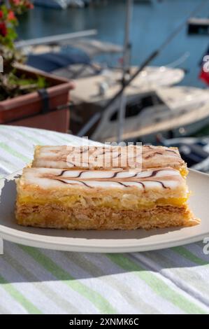 Portion de gâteau français mille feuilles, tranche de vanille ou de crème anglaise, pâte feuilletée Napoléon recouverte de crème pâtissière servie en plein air à Port Grimaud, France Banque D'Images