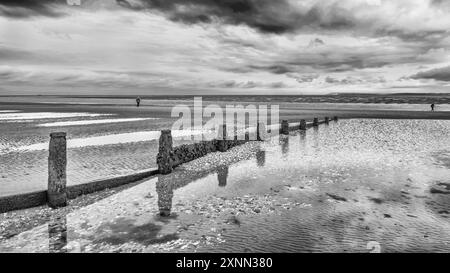 West Wittering Beach groynes en noir et blanc contre un ciel couvant Banque D'Images