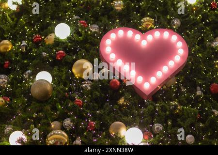 Arrière-plan flou, lumières bokeh en forme de cœur sur le sapin de Noël sont joliment décorées et le symbole du cœur signifie amour, amitié et gentillesse Banque D'Images