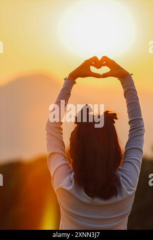 La silhouette de la fille peinte à la main est un symbole en forme de cœur de l'amour, de la compassion et de l'amitié avec une belle tranquillité sur un fond ensoleillé en th Banque D'Images