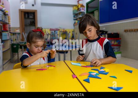 Enfants à la maternelle faisant des puzzles au bureau. Banque D'Images