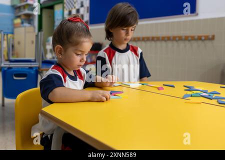 Enfants à la maternelle faisant des puzzles au bureau. Banque D'Images