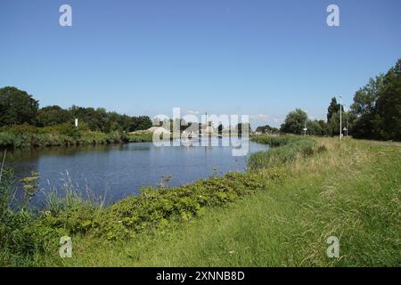 Paysage hollandais avec canal (Noordhollandsch Kanaal), moulin à vent (de Sluismolen, 1575), bateaux, pont flottant. Village de Koedijk. Été, juillet, Banque D'Images