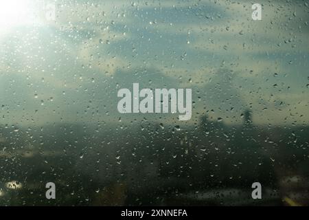Des gouttes de pluie tombent sur la fenêtre d'une maison dans une grande ville. Gros plan de pluie lente, jour pluvieux, averse abondante. Pluie dans la ville, fond pour une humeur triste. Banque D'Images