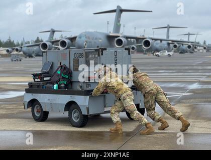 Edward Cho, aviateur senior de l'US Air Force, à gauche, et Radu Brujban, tous deux chefs d'équipage du 62d Aircraft maintenance Squadron, poussent un générateur loin d'un C-17 Globemaster III à la base interarmées Lewis-McChord, Washington, le 29 juillet 2024. Les chefs d’équipage veillent à ce que les aéronefs soient entretenus, sûrs, opérationnels et prêts à voler à tout moment. (Photo de l'US Air Force par Airman 1st Class Megan Geiger) Banque D'Images