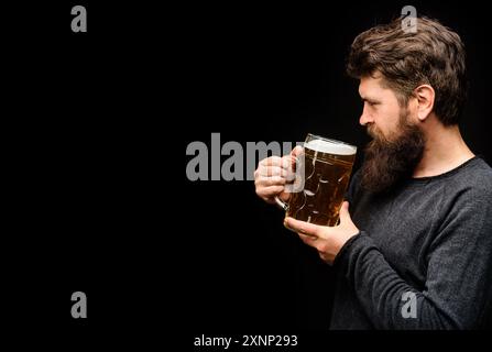 L'homme barbu de la bière lager dans une tasse. Célébration de l'Oktoberfest. Brasseur mâle avec verre de bière artisanale. Beau gars dégustant de la bière pression au bar ou au pub. Banque D'Images