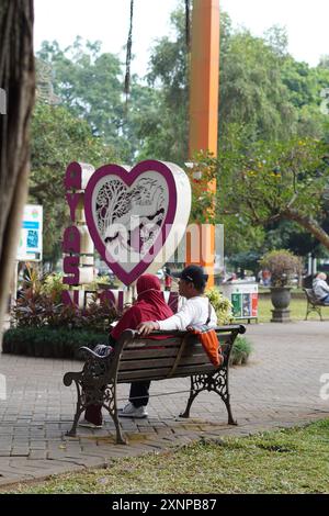 Un couple se reposant sur un banc de parc le matin dans un parc au milieu de la ville Banque D'Images