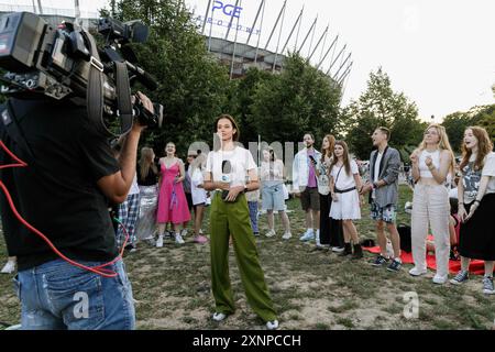 Une correspondante de TVN24 se prépare pour une émission en direct parmi les fans de Taylor Swift qui apprécient sa performance à l'extérieur du stade où son premier des trois concerts en Pologne se tient dans le cadre de l'Eras Tour. La chanteuse américaine Taylor Swift jouera trois concerts à Varsovie, en Pologne, les 1er, 2 et 3 août dans le cadre de son Eras Tour. L'événement a lieu au stade national (PGE Stadion Narodowy). Des milliers de personnes de Pologne et d'autres pays assisteront au concert lui-même. Cependant, certains fans, connus sous le nom de Swifties, se sont rassemblés autour du stade pour entendre la star. (Photo de Volha Shu Banque D'Images
