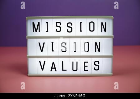 Texte du panneau de lettres Mission Vision Values sur LED Lightbox sur fond rose et violet Banque D'Images