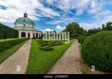 Vue basse sur le jardin fleuri ornemental avec des buissons verts, journée ensoleillée d'été, bâtiment historique rond dans le centre, tourisme en République tchèque Banque D'Images