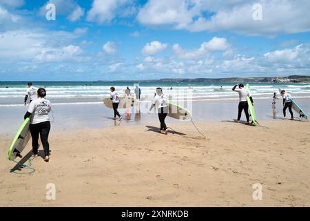 Un groupe d'apprenants novices de surf débutant une leçon de surf avec l'école de surf SSS sur Towan Beach à Newquay en Cornouailles au Royaume-Uni. Banque D'Images
