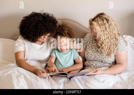 Mère lisant avec ses filles au lit Banque D'Images