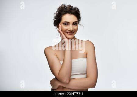 Une jeune femme sourit rayonnamment en posant pour un portrait dans un cadre de studio. Banque D'Images