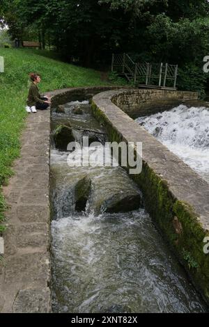 Une dame de la zone zen assise méditant près de la rivière Banque D'Images