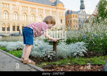 Mignon petit garçon marchant le long des rues pavées colorées de Riga. Enfant explorant la ville lettone. Vie urbaine dynamique dans la capitale de la Lettonie. Banque D'Images