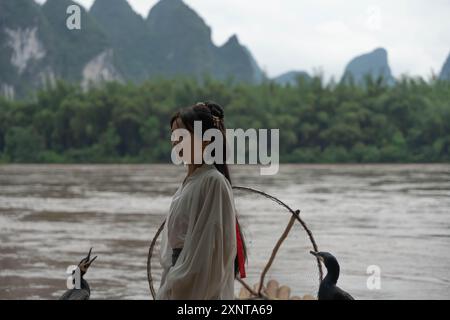 Fille chinoise fixe les cheveux longs sur la scène traditionnelle des pêcheurs. Vêtements traditionnels Banque D'Images