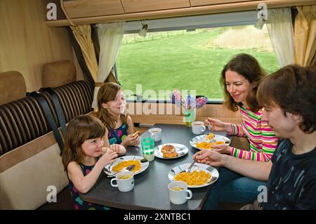 Famille mangeant ensemble à l'intérieur du RV, parents et enfants voyagent en camping-car (camping-car, caravane) en vacances en famille avec enfants Banque D'Images