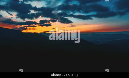 Assistez à la transition étonnante du jour à la nuit dans les montagnes des Carpates tandis que des couleurs vibrantes remplissent le ciel pendant un coucher de soleil à couper le souffle. Banque D'Images