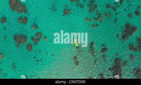 Paddle board dans les eaux turquoises, l'homme jouit d'une vue paradisiaque d'en haut, entouré par l'océan et le ciel. Toile de fond parfaite pour une journée de détente dans la nature Banque D'Images