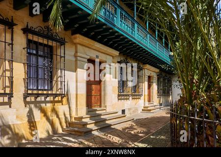 Bâtiment colonial historique de Bogota aux couleurs vives, aux barres de fenêtres en fer forgé et entouré de palmiers. Capture le charme de l'arc urbain Banque D'Images