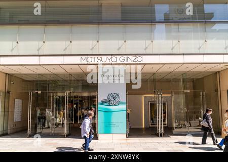 Les gens marchent sous le soleil éclatant près de l'entrée du magasin phare Matsuya Ginza avec des expositions de Tiffany & Co et Dior. Banque D'Images