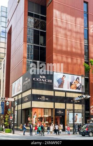 Le magasin Coach à la mode dans la Ginza sur la rue Namiki-dori, les gens devant le magasin attendent pour utiliser le passage piétonnier en face. Vertical. Banque D'Images