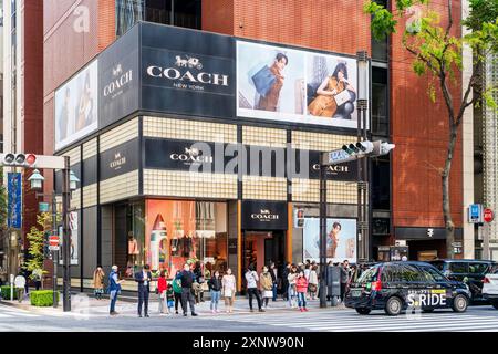 Le magasin Coach à la mode dans la Ginza sur la rue Namiki-dori, les gens devant le magasin attendent pour utiliser le passage piétonnier en face. Banque D'Images