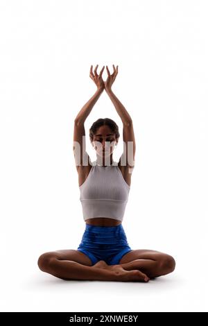 Jeune femme de couleur effectuant une pose de yoga méditative, assise en position lotus avec les bras levés. Démontrer la pleine conscience, l'équilibre et le pois intérieur Banque D'Images
