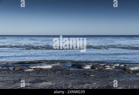 Côte de la mer Baltique un jour d'hiver, photo de paysage du golfe de Finlande. Les floes de glace fondantes avec du sable reposent sur la côte gelée, fond d'hiver naturel Banque D'Images