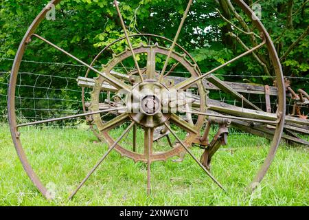 Gros plan d'une roue de machine agricole vintage et rouillée avec un fond vert luxuriant. Derbyshire Royaume-Uni. Banque D'Images