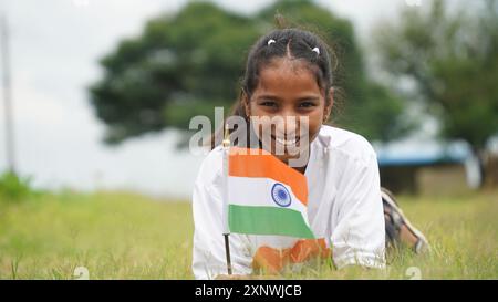 Étudiant indien ou enfants tenant ou agitant tricolore avec de la verdure en arrière-plan, célébrant l'indépendance ou le jour de la République. Har Ghar Tiranga Banque D'Images