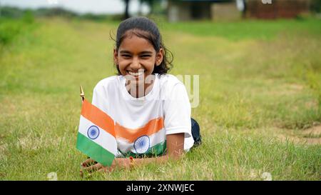 Étudiant indien ou enfants tenant ou agitant tricolore avec de la verdure en arrière-plan, célébrant l'indépendance ou le jour de la République. Har Ghar Tiranga Banque D'Images