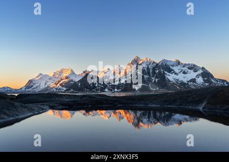 Lumières chaudes du matin sur les montagnes enneigées reflétées dans une piscine près du fjord, Vareid, municipalité de Flakstad, îles Lofoten, Norvège, Scandinavie, Europe Banque D'Images