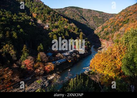 Forêts d'automne avec rivière Katsura bleu profond avec toits de temple sur la rive de la rivière à Arashiyama de Kyoto, Honshu, Japon, Asie Banque D'Images