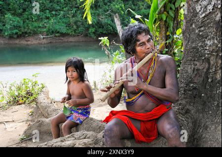 Joueur de flûte et petite fille, communauté autochtone Embera vivant près de la rivière Chagres dans le Parc National Chagres, République du Panama Banque D'Images