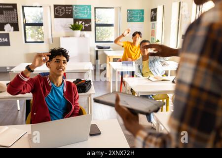 Au lycée, les élèves lèvent la main pour répondre à la question de l'enseignant en classe Banque D'Images