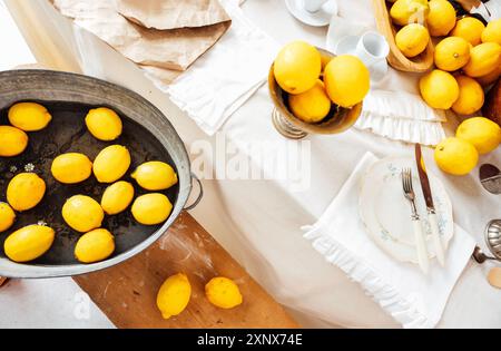 Citrons frais juteux et marguerites dans l'eau dans un bassin en métal vintage. Vue de dessus. Banc rétro en bois avec agrumes jaunes. Tissu blanc dans le backgrou Banque D'Images