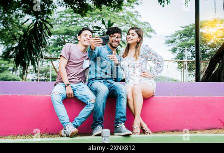 Style de vie de trois amis assis dans un parc prenant un selfie, trois amis adolescents assis dans un parc prenant des selfies. Rencontre de trois heureux amis Banque D'Images