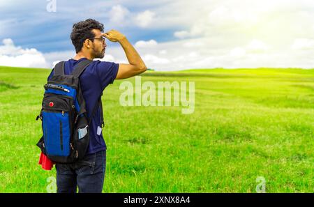 Portrait de Backpacker masculin dans un champ regardant au loin Banque D'Images