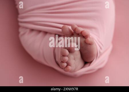 Pied de bébé sur couvre-lit souple rose, couverture. Détail des jambes d'un nouveau-né. Banque D'Images