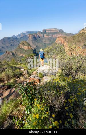 Jeune homme debout sur un rocher dans un paysage de canyon, coude de rivière à Blyde River Canyon avec trois Rondawels pic, vue sur le canyon avec Blyde River et Banque D'Images