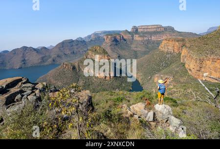 Jeune homme debout sur un rocher dans un paysage de canyon, coude de rivière à Blyde River Canyon avec trois Rondawels pic, vue sur le canyon avec Blyde River et Banque D'Images