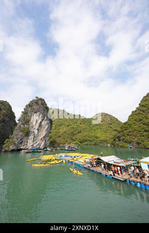 Les vacanciers font la queue pour un kayak sur une jetée, derrière les rochers karstiques dans la baie de LAN Ha, baie d'Halong, Vietnam Banque D'Images